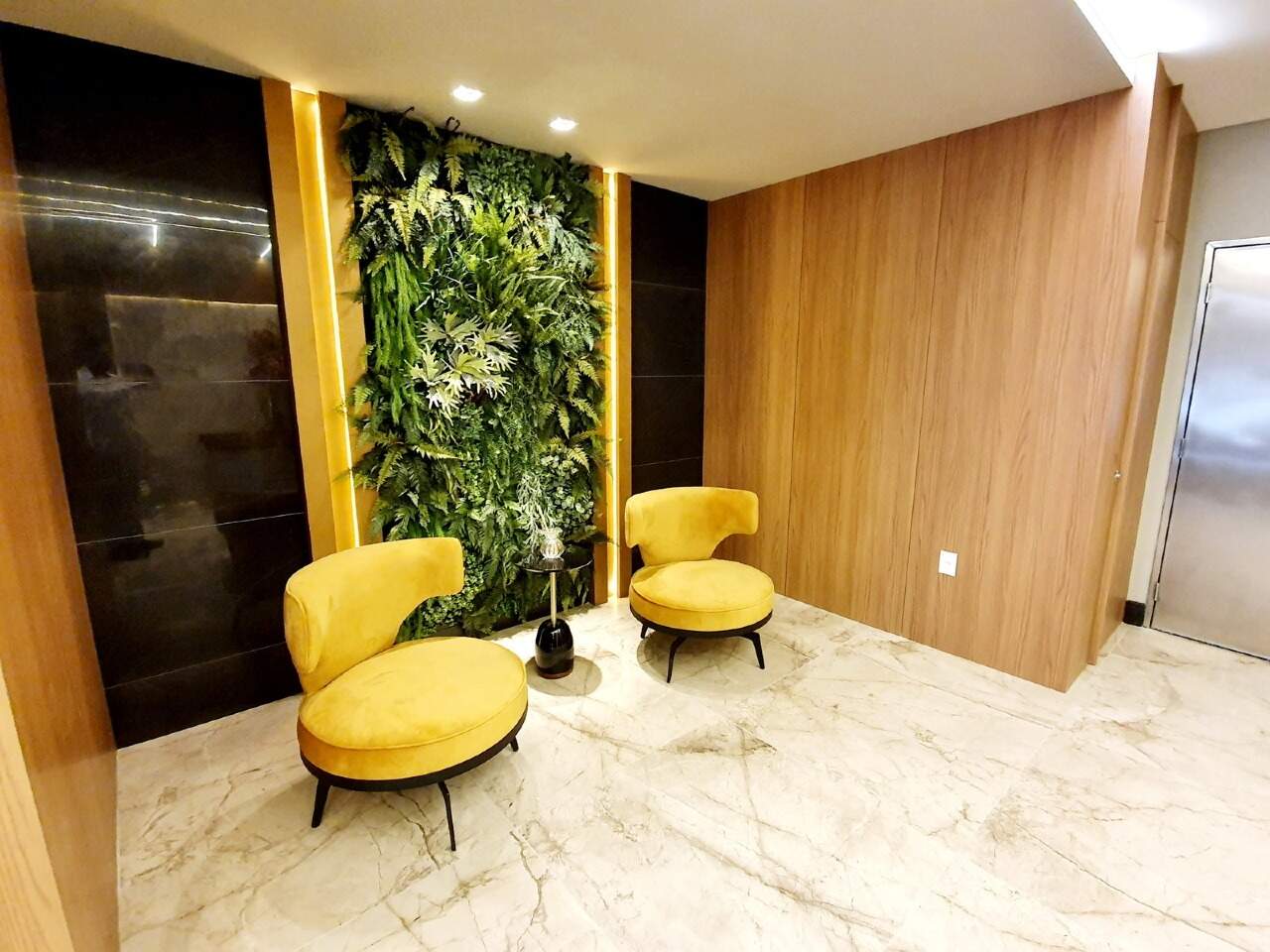 Hall com poltronas amarelas e jardim vertical