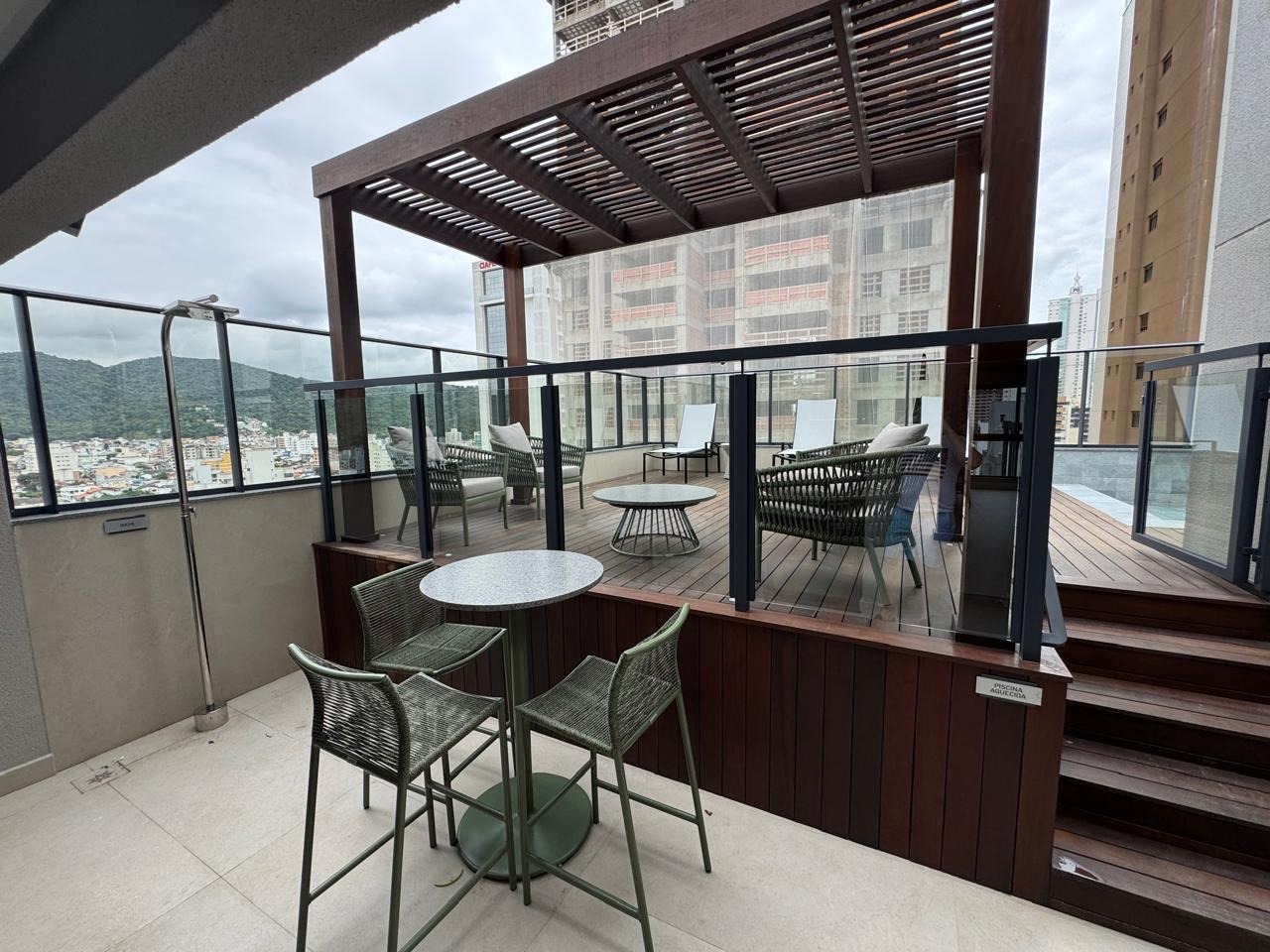 Deck do rooftop com mesas e vista da cidade