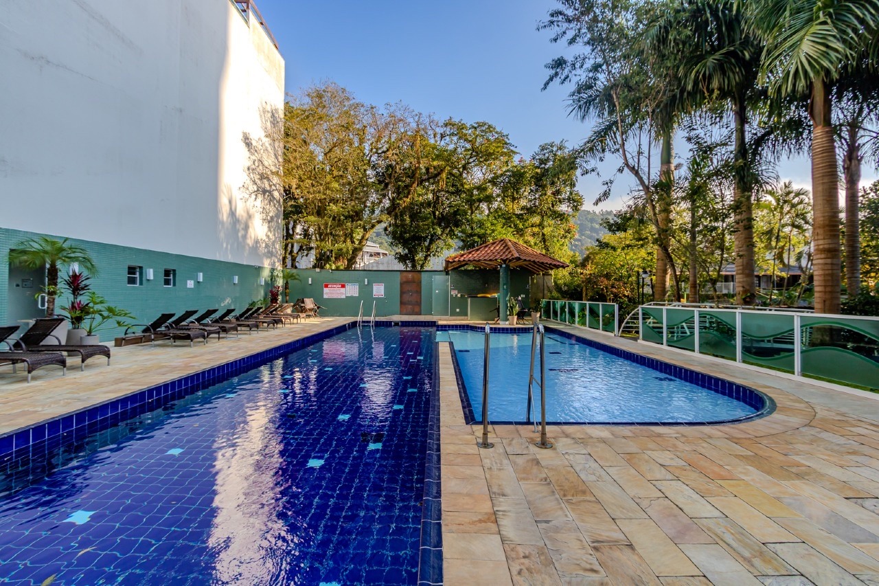 Piscina com deck de pedra e jardim ao redor