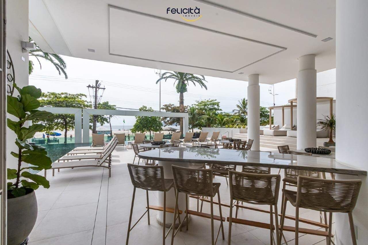 Área coberta junto à piscina, com mesas e vista para a Avenida Atlântica