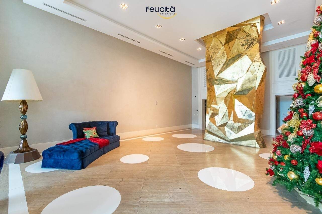 Hall social com obra de arte dourada e estar mobiliado