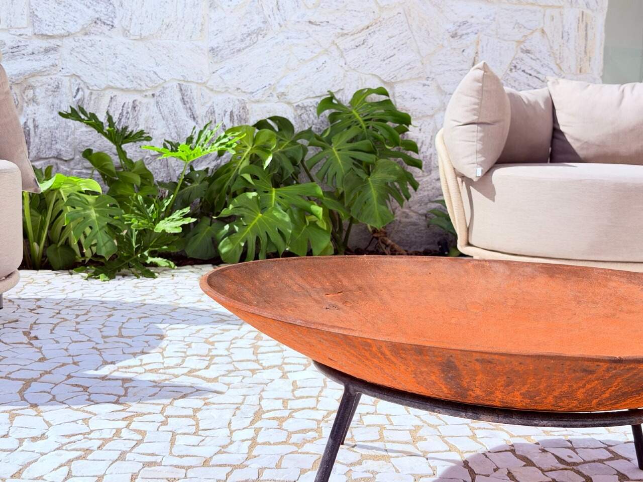 Pátio do térreo com fogo de chão, poltronas e jardim