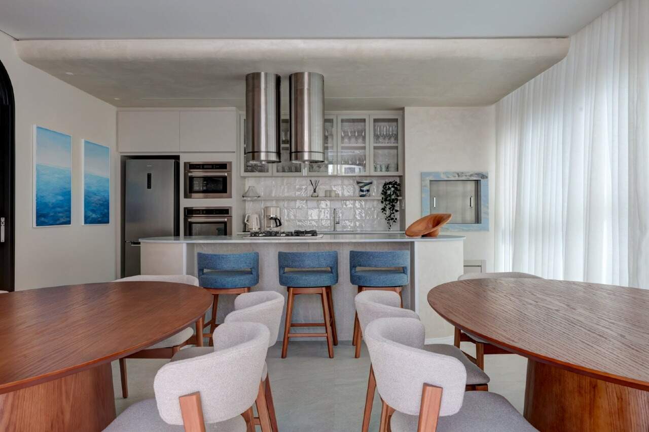 Espaço gourmet com cozinha aberta e mesas de jantar