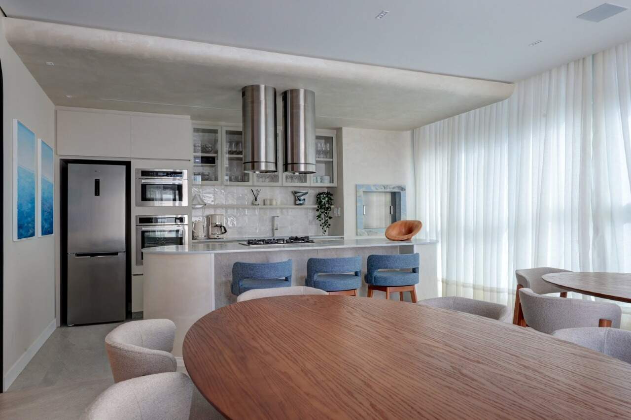 Espaço gourmet com mesa oval e cozinha equipada
