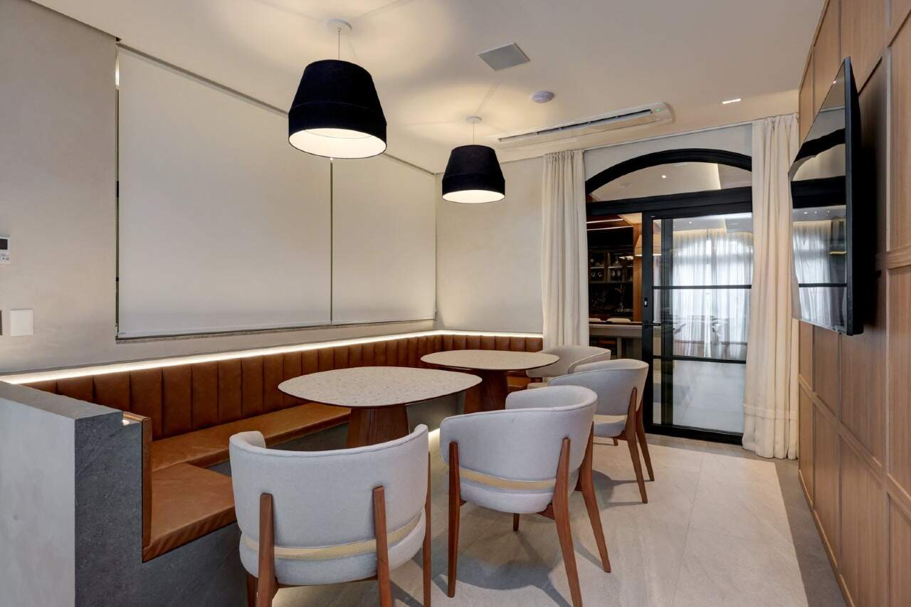 Lounge com mesas, banco estofado e TV