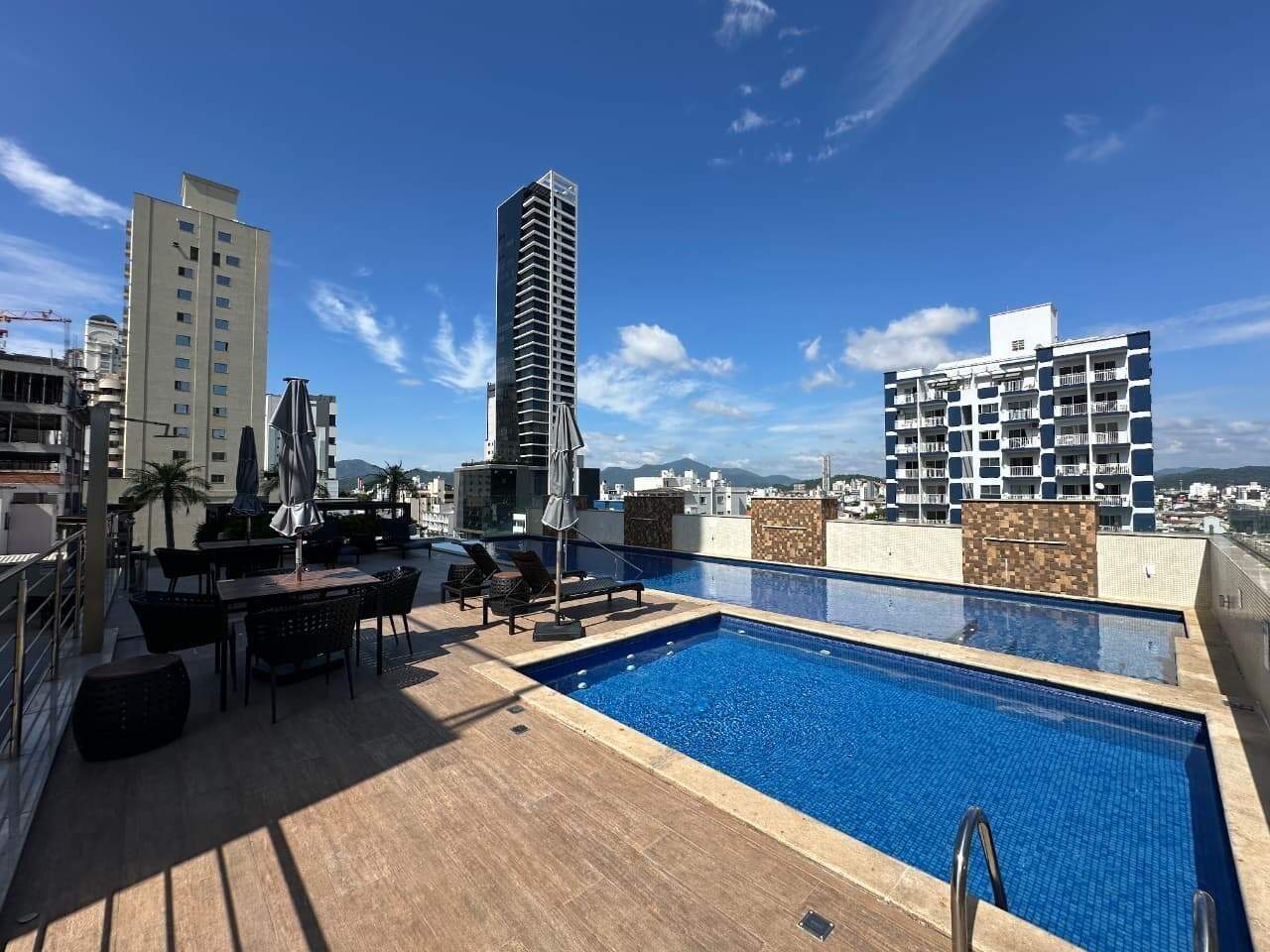 Piscina com deck e espreguiçadeiras no terraço de lazer