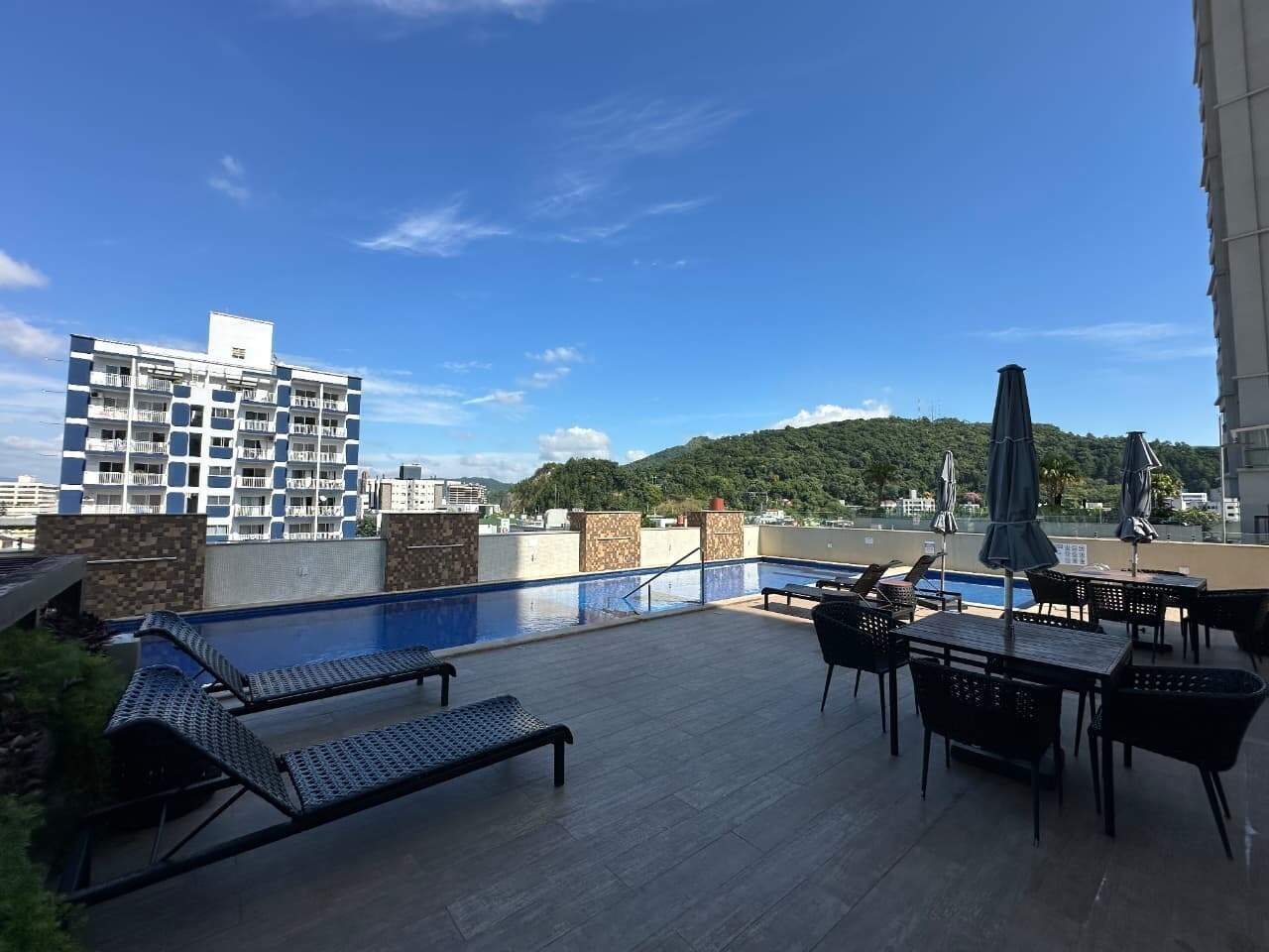 Deck da piscina com mesas e guarda-sóis