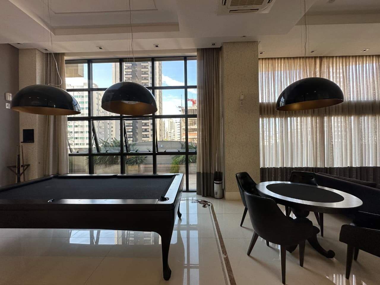 Salão de jogos com mesa de sinuca e mesa redonda
