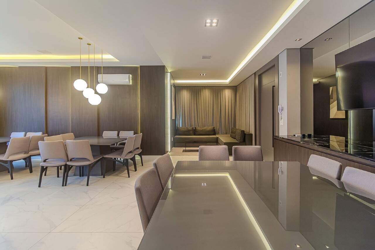 Salão de festas com mesa comprida e cozinha integrada