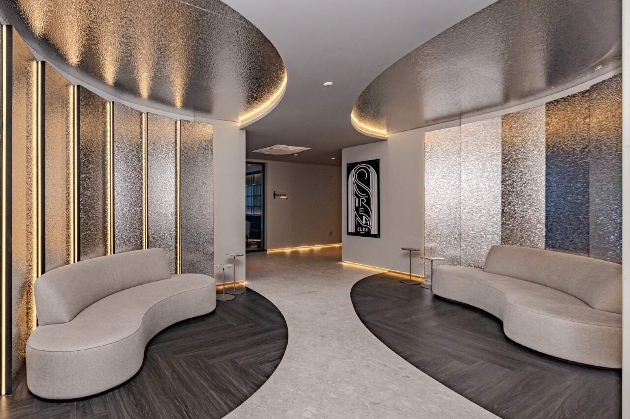 Estar do hall com poltronas curvas e teto iluminado