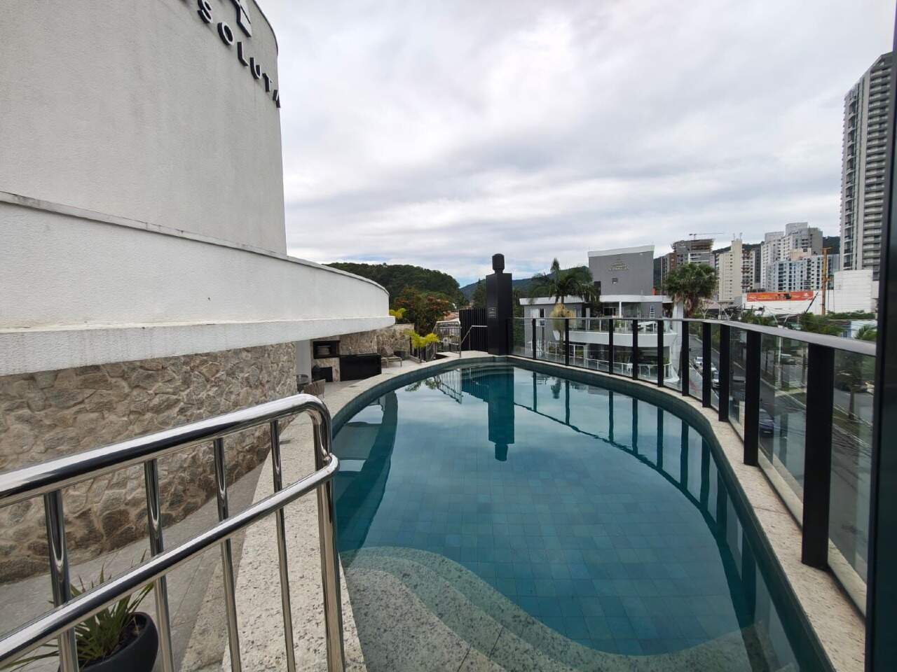 Piscina com guarda-corpo de vidro e vista do bairro
