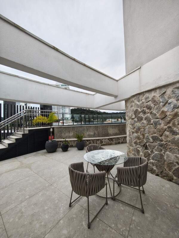 Terraço de lazer com mesas e parede de pedra