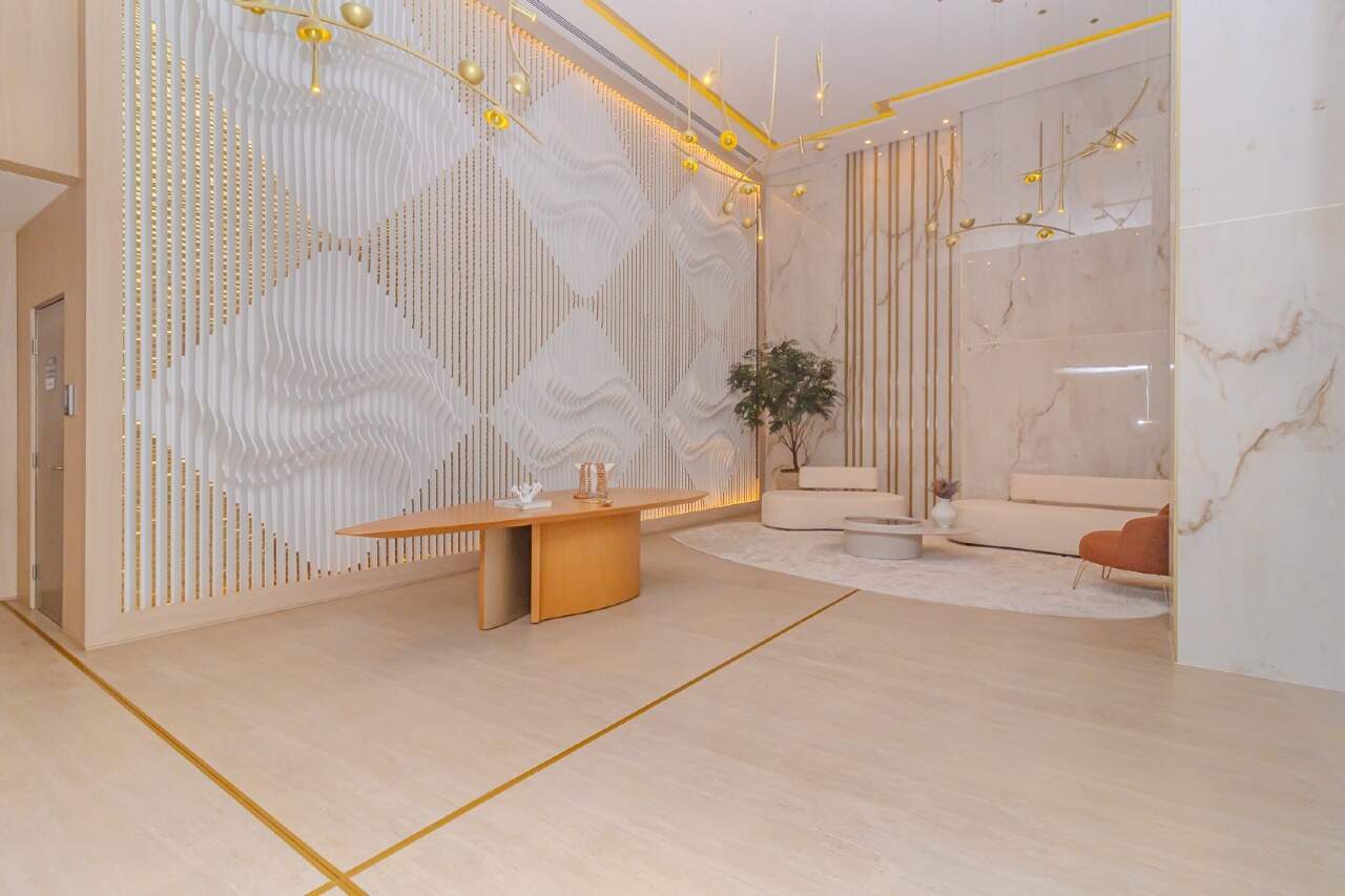 Hall de entrada da Torre Brisa, com mesa de madeira e luminárias douradas