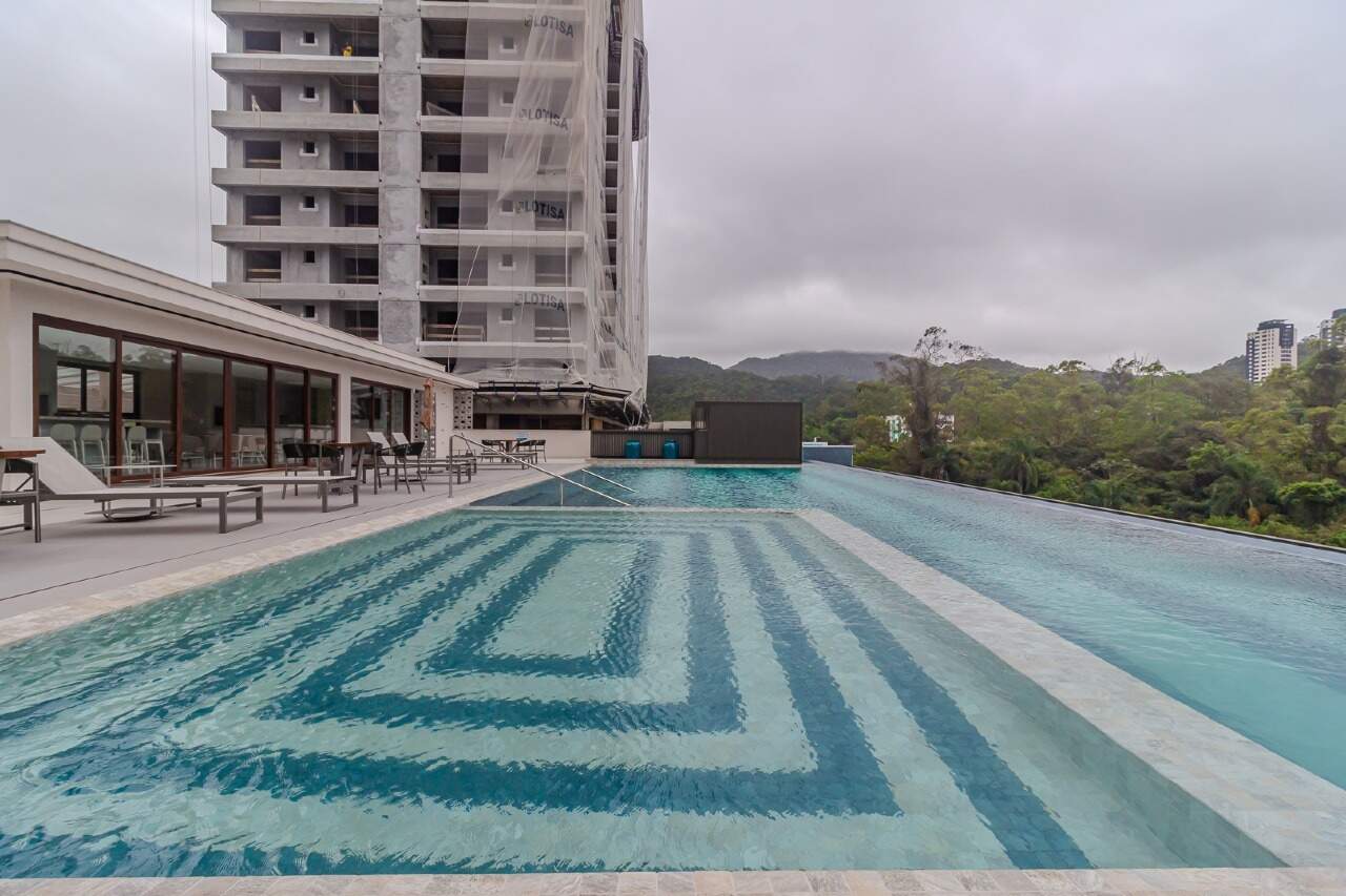 Piscina com desenho de pastilhas e o salão ao fundo