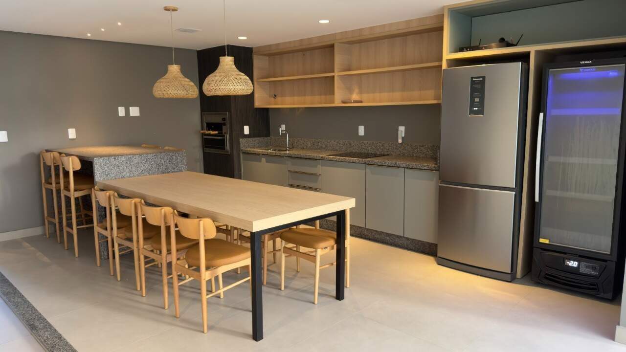 Espaço gourmet com mesa comunitária, geladeira e adega
