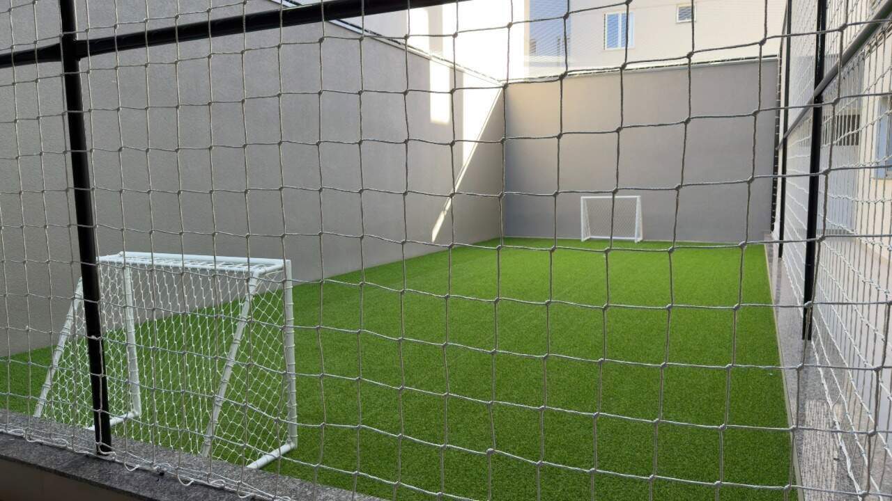 Campo de futebol com grama sintética e rede de proteção