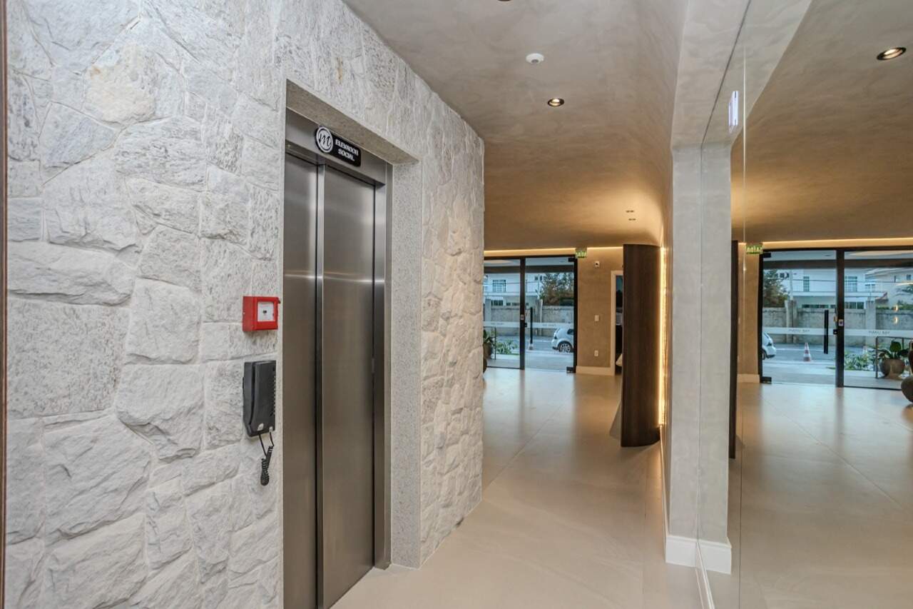Hall dos elevadores com parede de pedra
