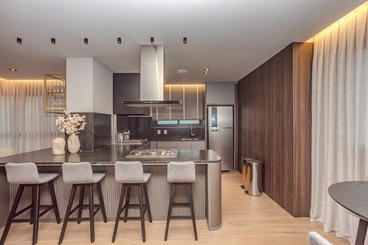 Espaço com ilha, cooktop e coifa para receber convidados