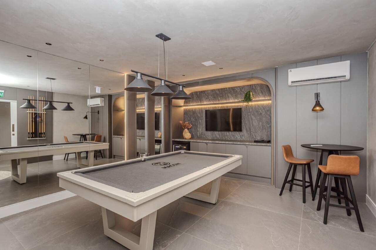 Sala de jogos com mesa de sinuca e bancada com TV