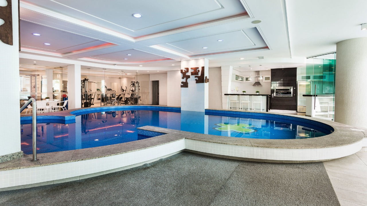 Piscina coberta do La Madeson, com deck e a academia ao fundo