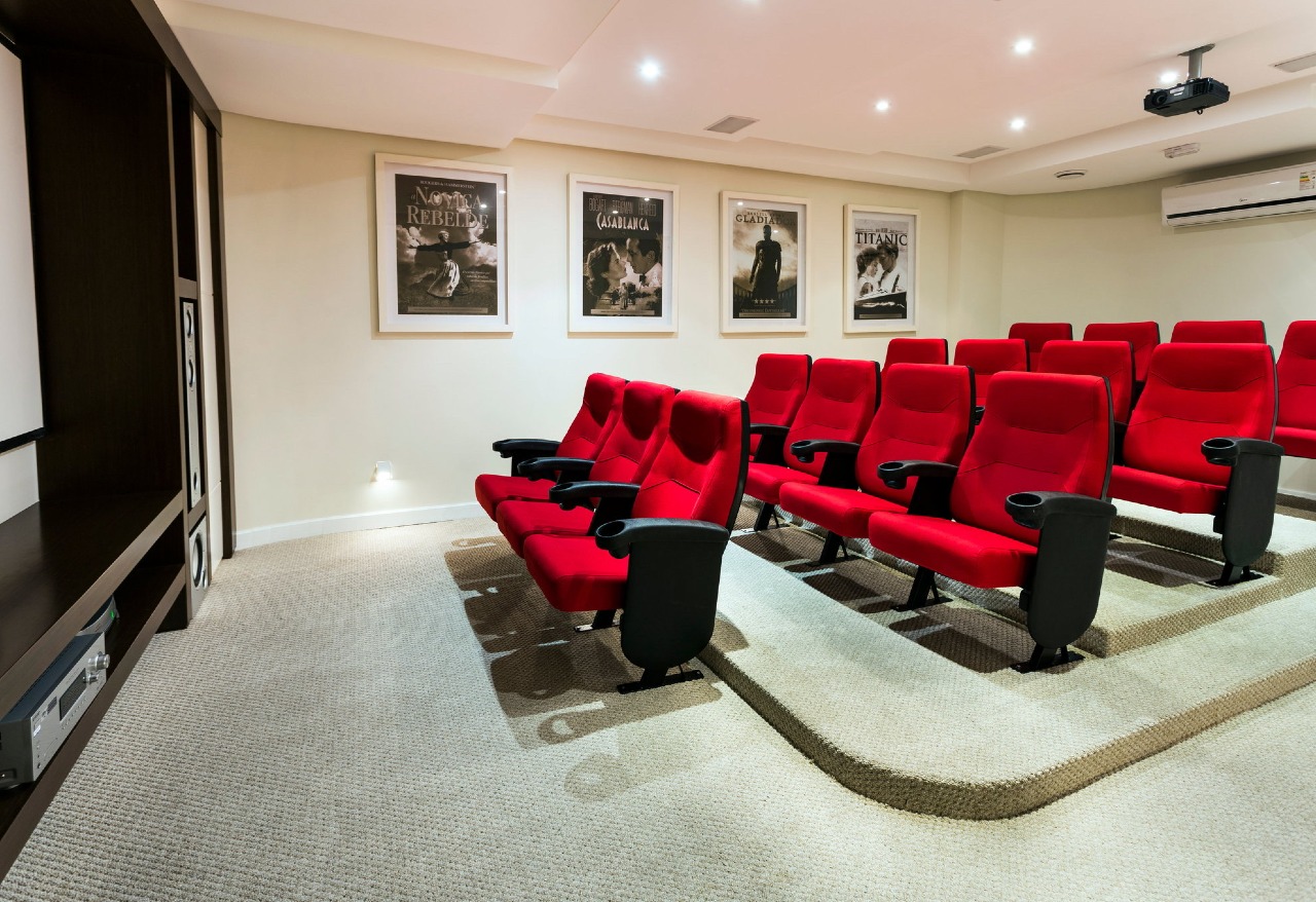 Sala de cinema com poltronas vermelhas e projetor
