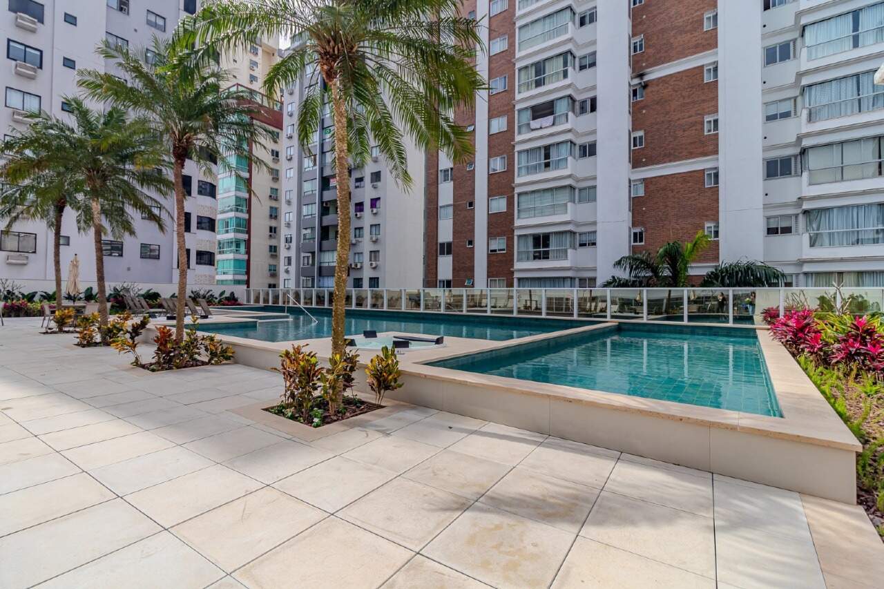 Piscinas adulto e infantil com palmeiras