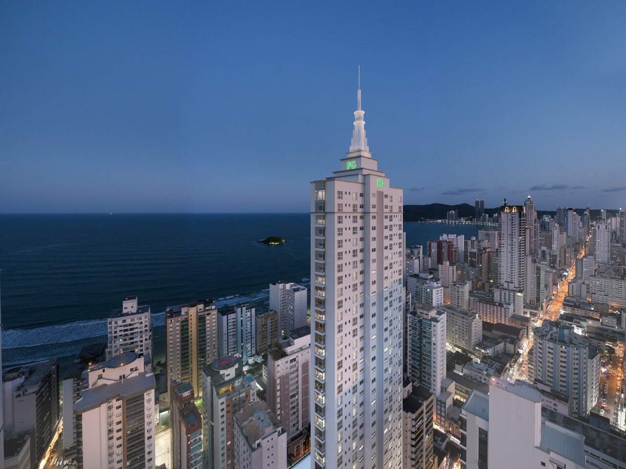 Pináculo do Grand Place Tower ao anoitecer, com o mar e a cidade (imagem ilustrativa)