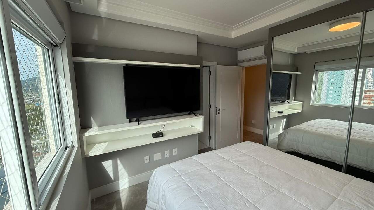 Suíte com painel de TV e armário espelhado