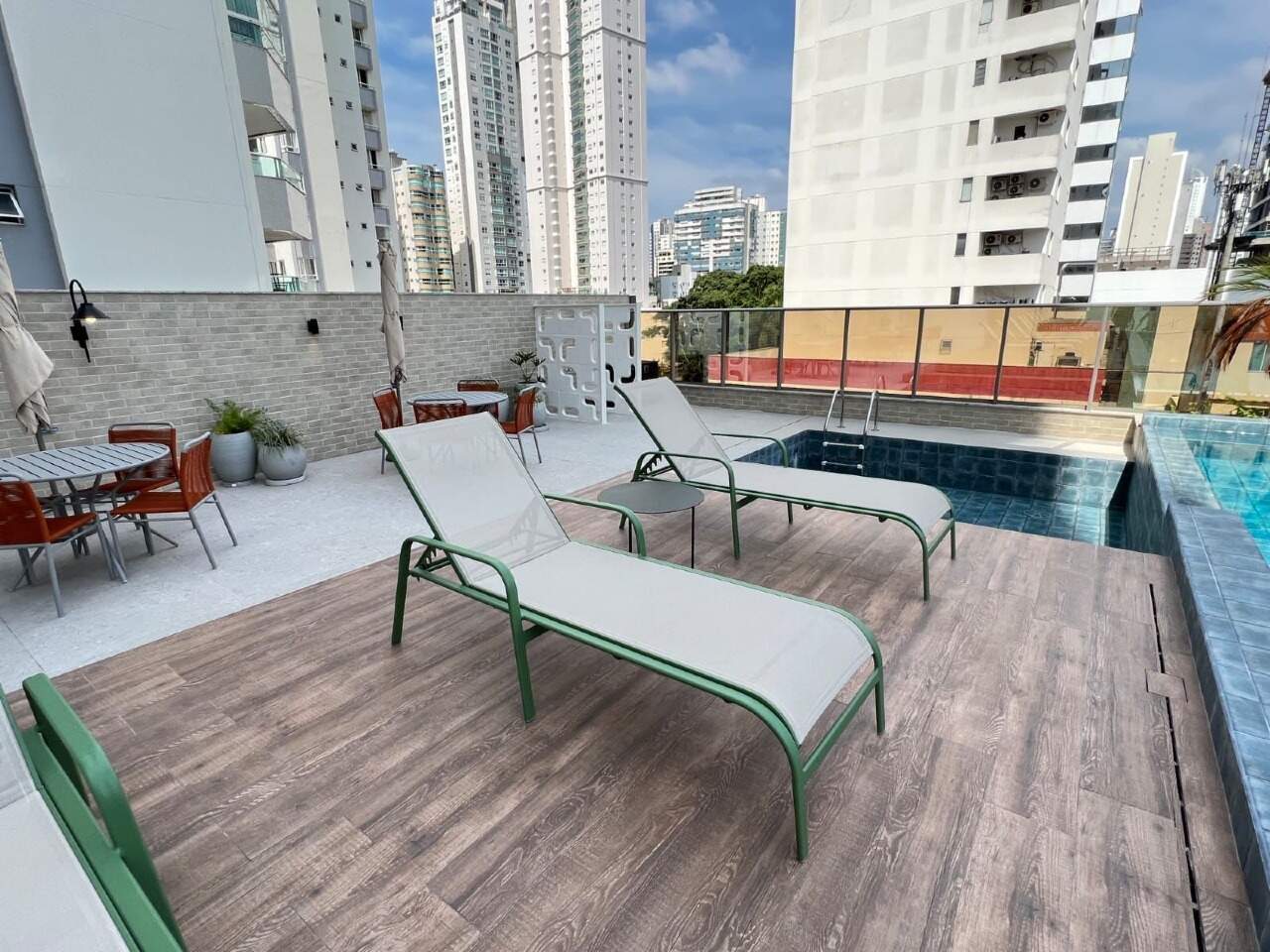 Deck da piscina com espreguiçadeiras e mesas