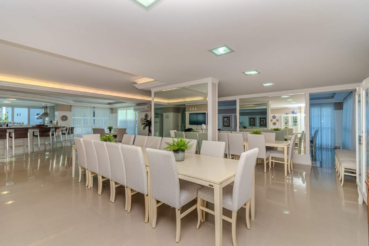 Salão de festas com mesa longa e cozinha integrada