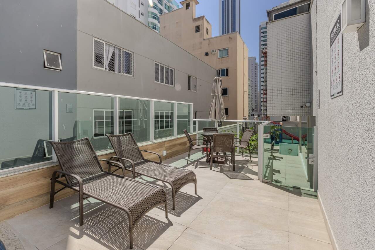 Solário com espreguiçadeiras e mesa ao lado da piscina