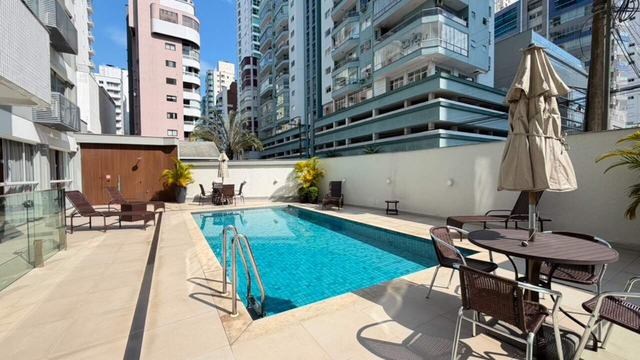 Deck da piscina com ombrelone, mesa e cadeiras