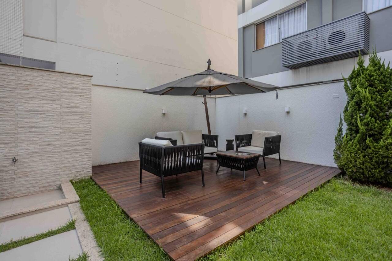 Lounge no deck, com sofás, mesa e ombrelone