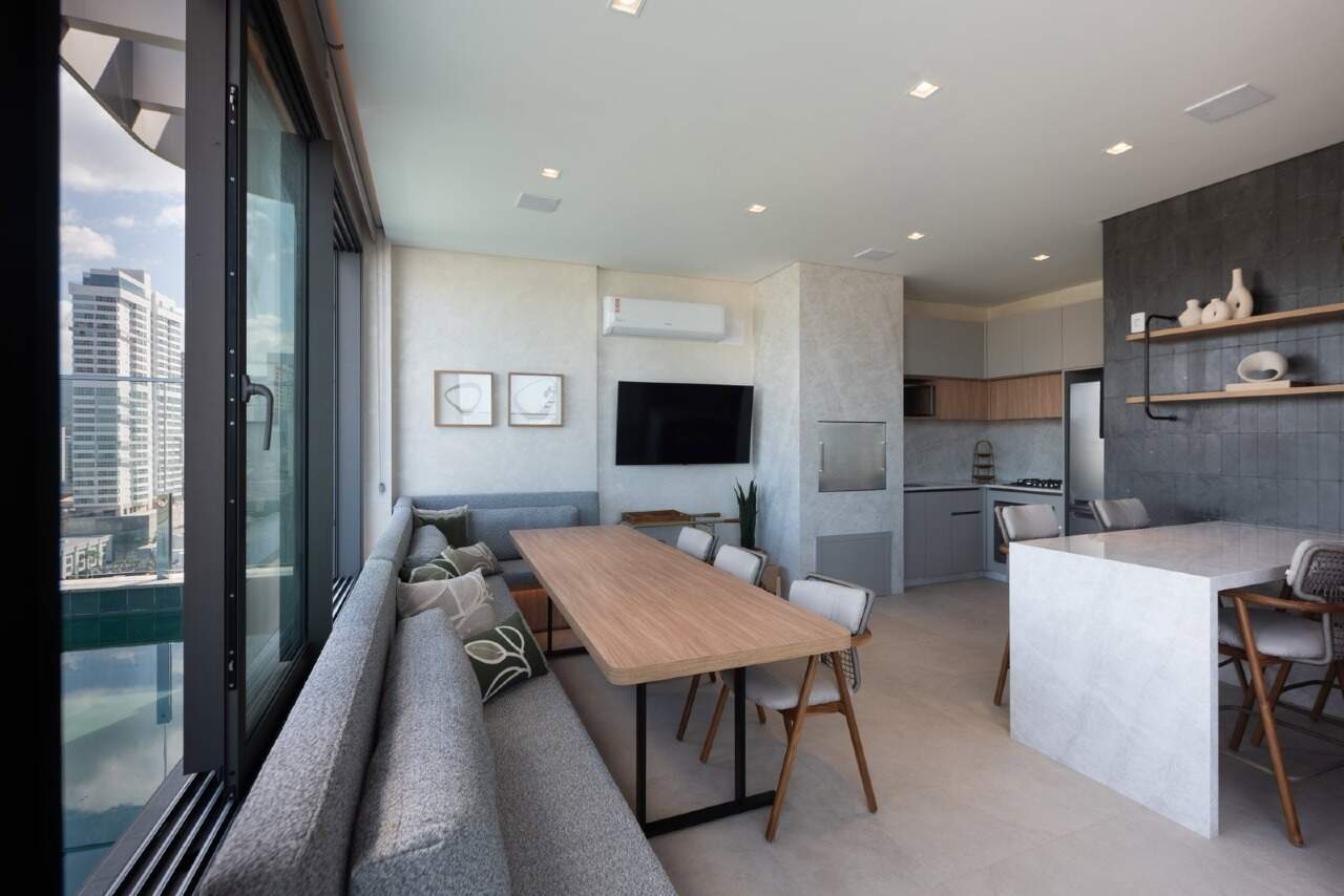 Espaço gourmet do rooftop com mesa, sofá e cozinha equipada
