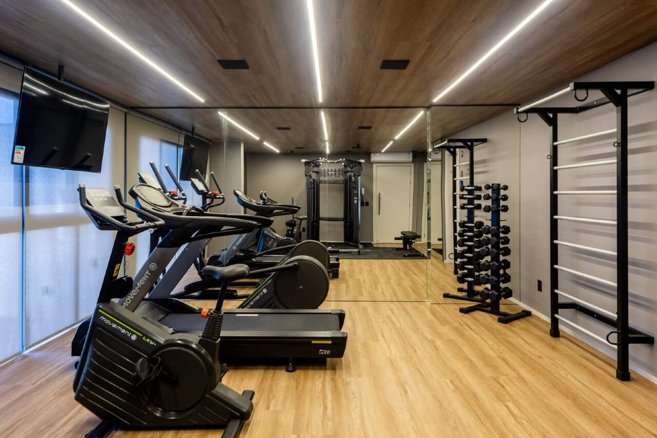 Academia equipada com esteiras, bicicletas e estação de musculação