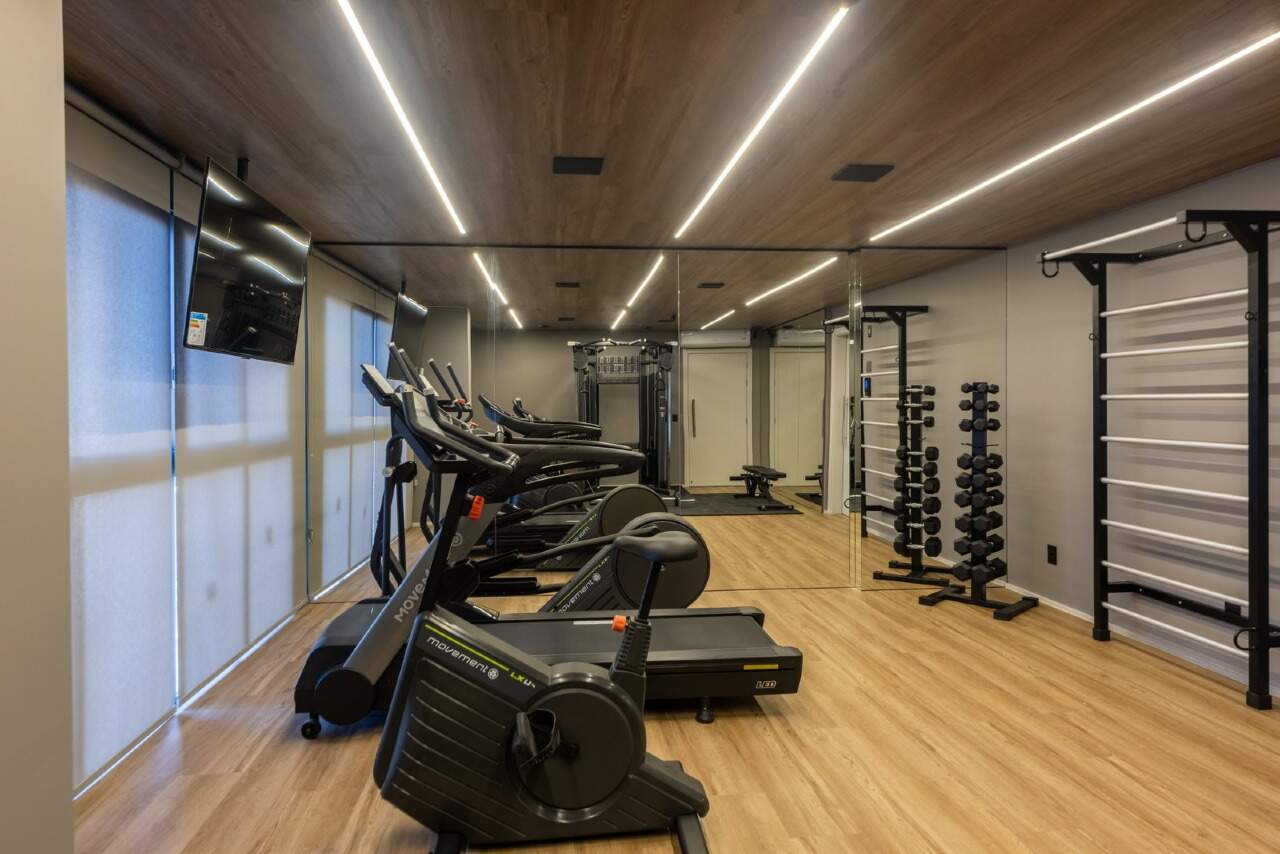 Academia com piso de madeira, espelhos e aparelhos de musculação