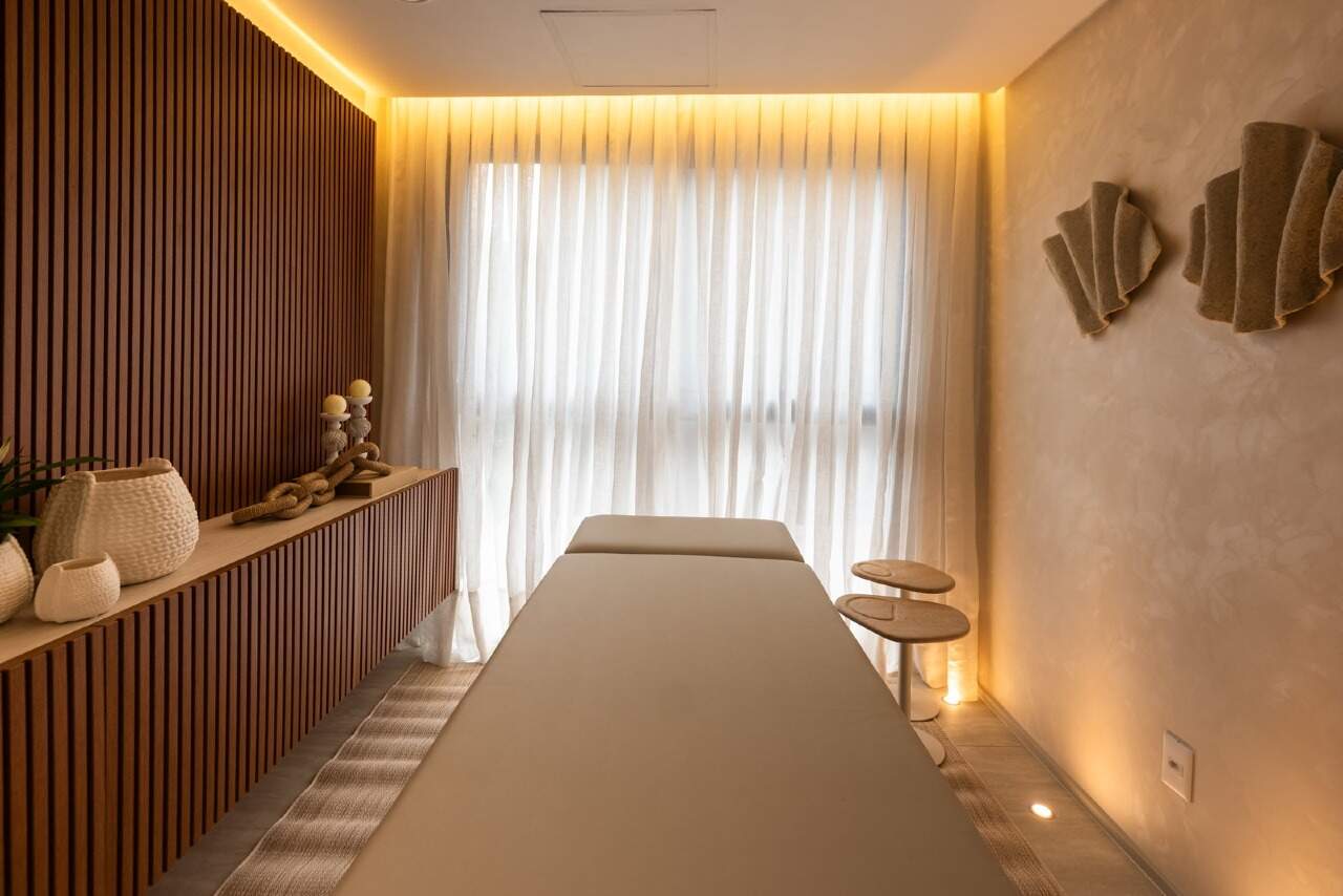 Sala de massagem com maca e painel de madeira ripada