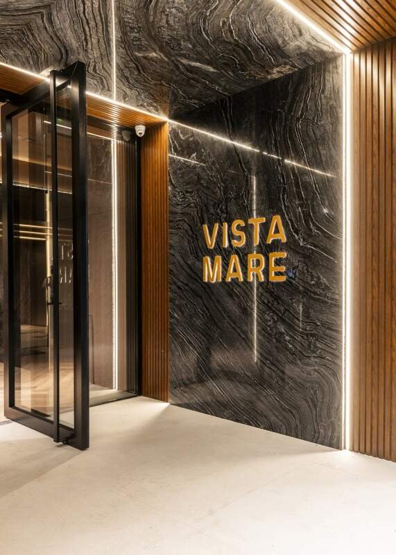 Porta de acesso do hall com o nome Vista Mare em pedra escura