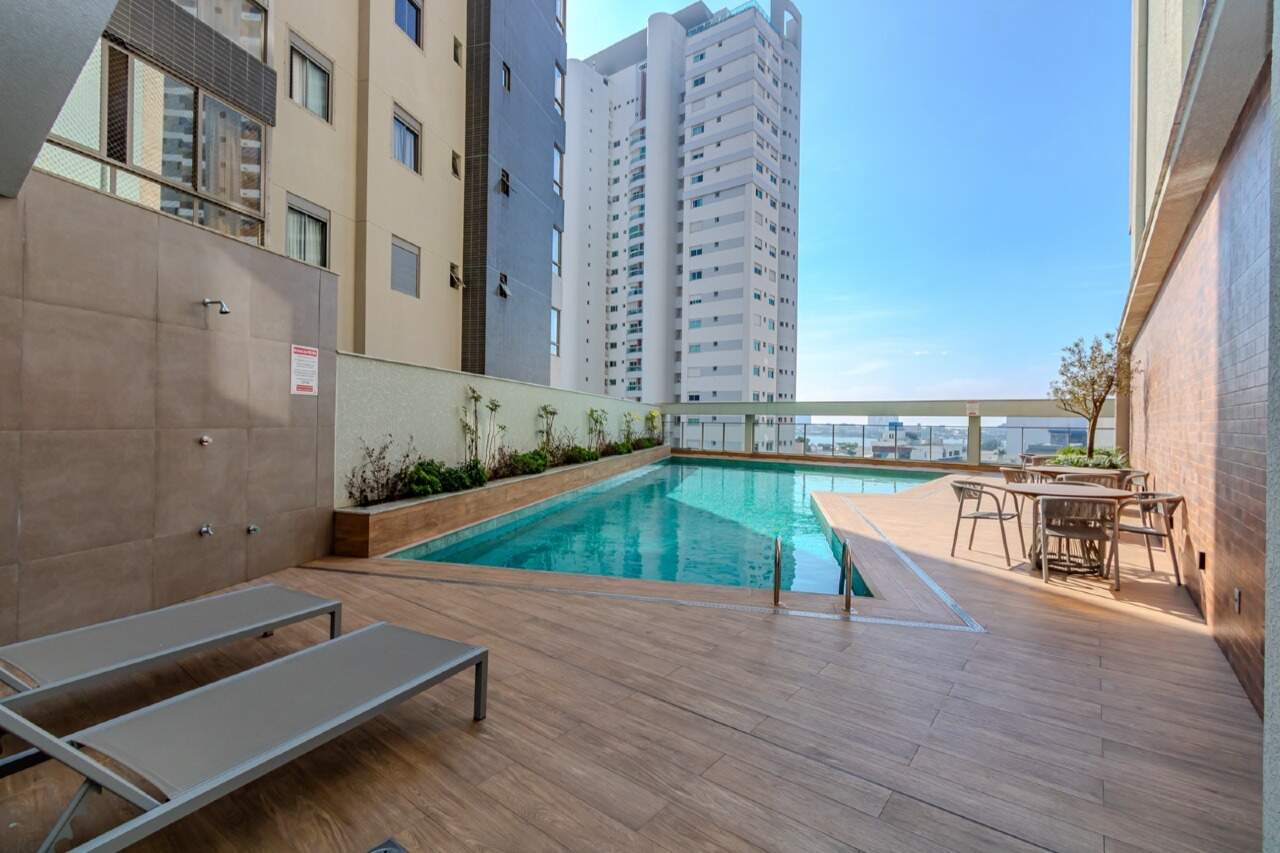 Piscina externa com deck de madeira e mesas