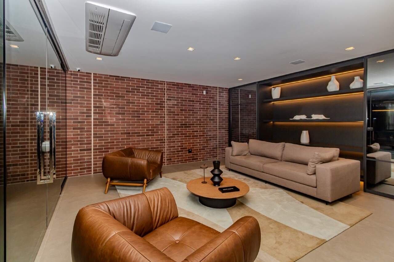 Lounge com sofás, poltronas de couro e parede de tijolos
