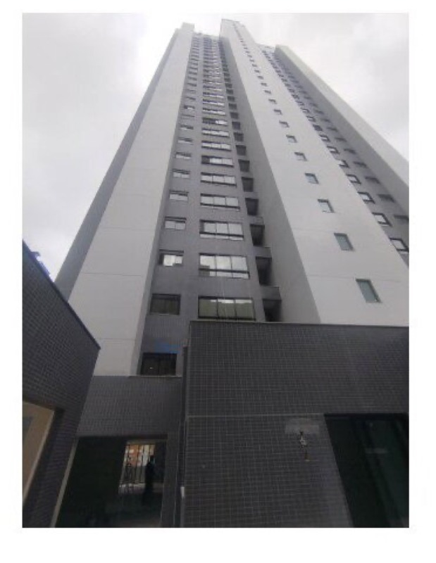 Base da torre com revestimento cerâmico escuro e acesso social, em fase final de obra