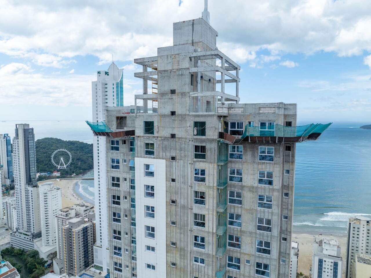 Topo da torre em obra, visto de drone, com a orla e a roda-gigante ao fundo