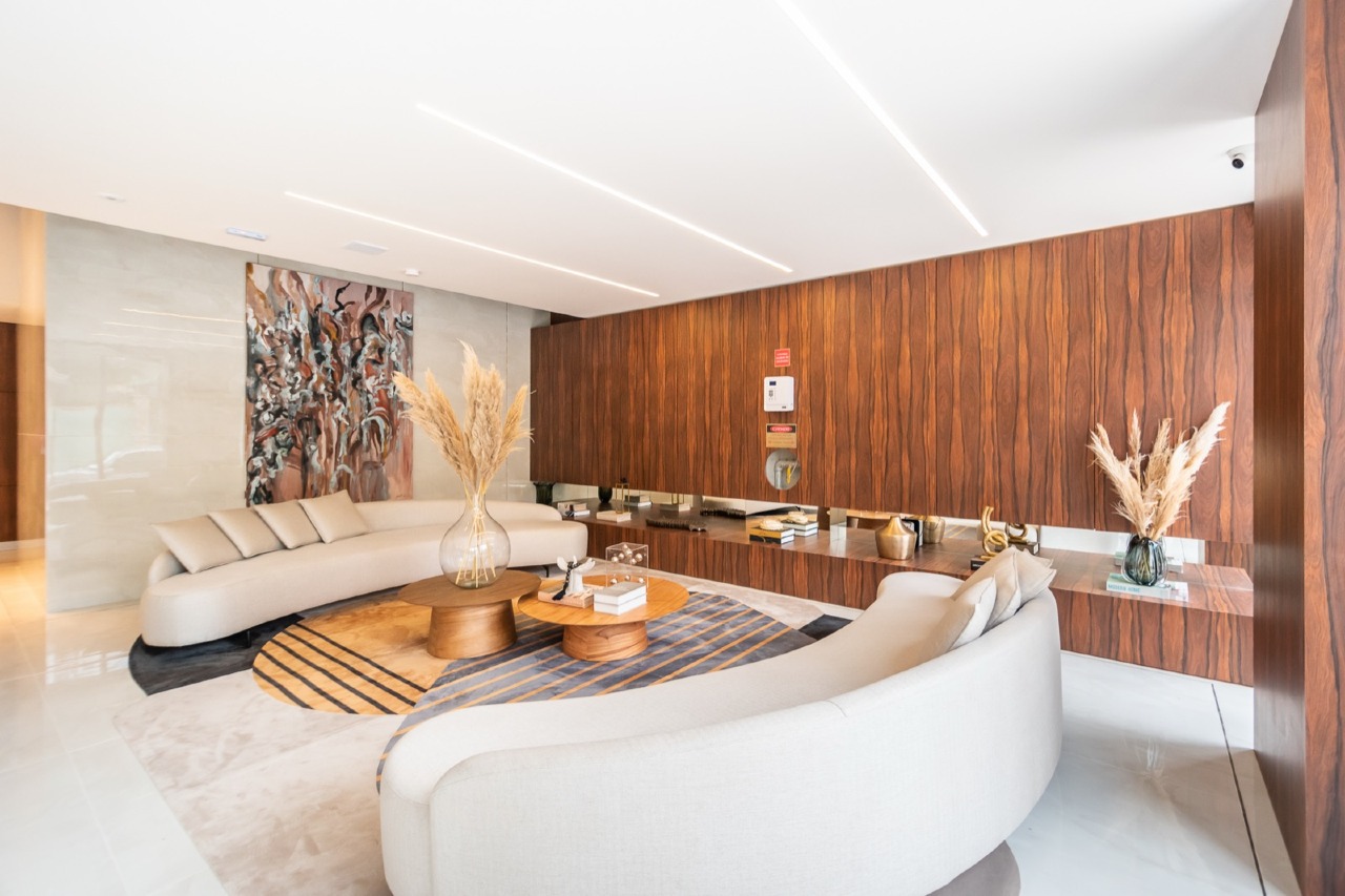 Lounge com sofá curvo e painel de madeira