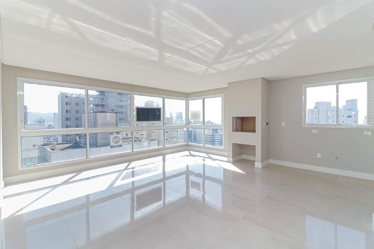 Apartamento à venda no Centro: Living com janelas amplas e churrasqueira. Foto real do apartamento.