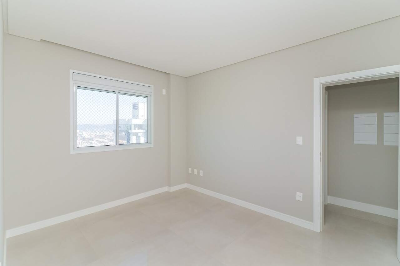 Apartamento à venda no Centro: Suíte com janela e acesso ao banheiro. Foto real.