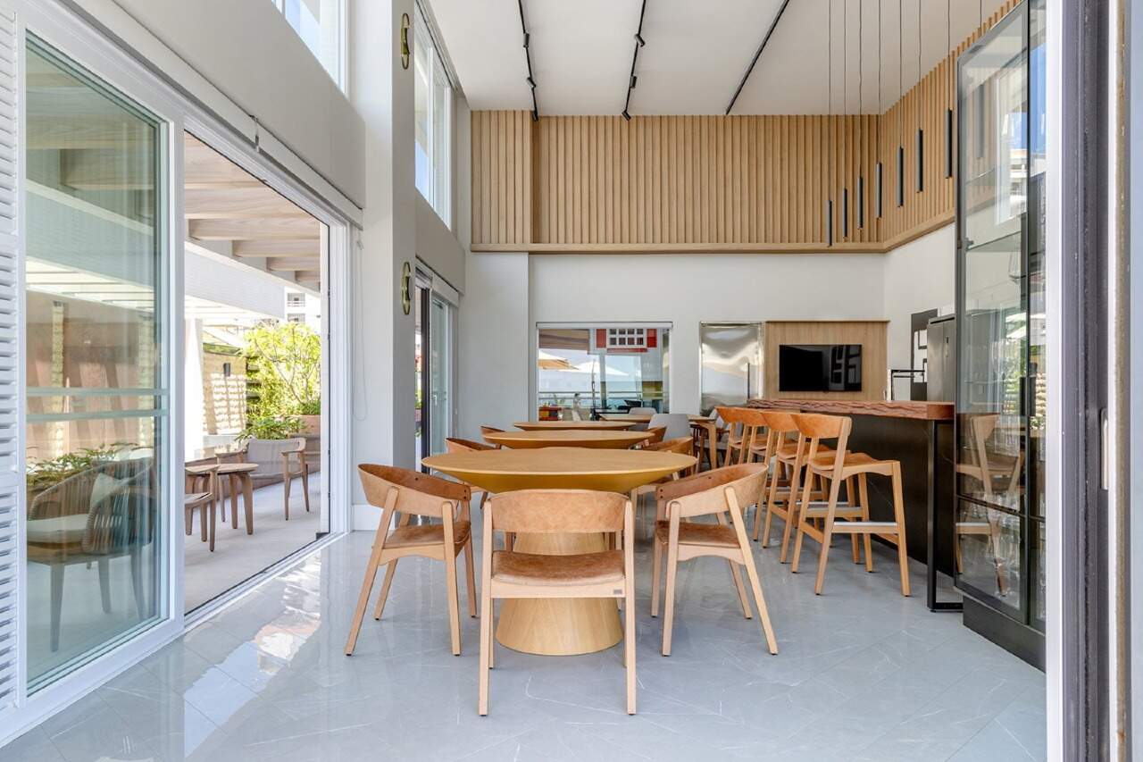 Apartamento à venda no Praia Brava: Salão de festas com mesas de madeira e pé-direito alto