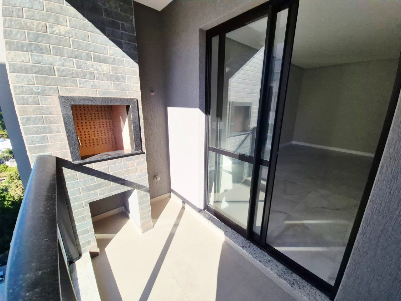 Apartamento à venda no Praia Brava: Sacada com churrasqueira a carvão e porta de vidro para o living