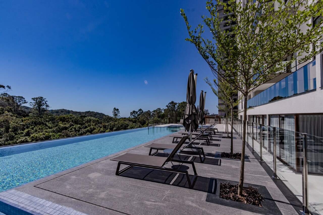 Apartamento à venda no Praia Brava: Piscina com espreguiçadeiras e borda de vidro no Torres da Brava Sirena