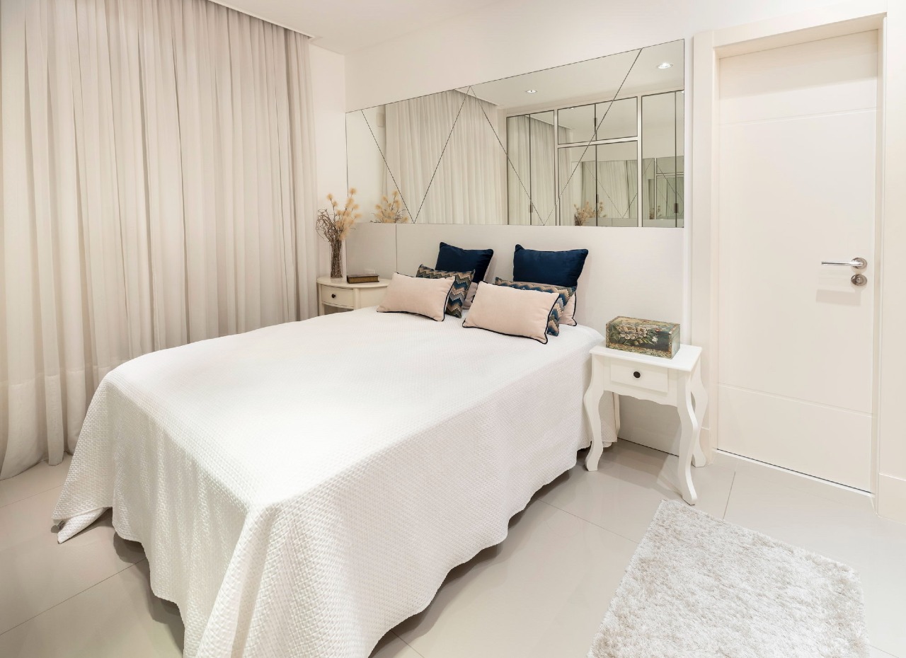 Apartamento à venda no Centro: Suíte com painel de espelhos atrás da cama e cortinas claras