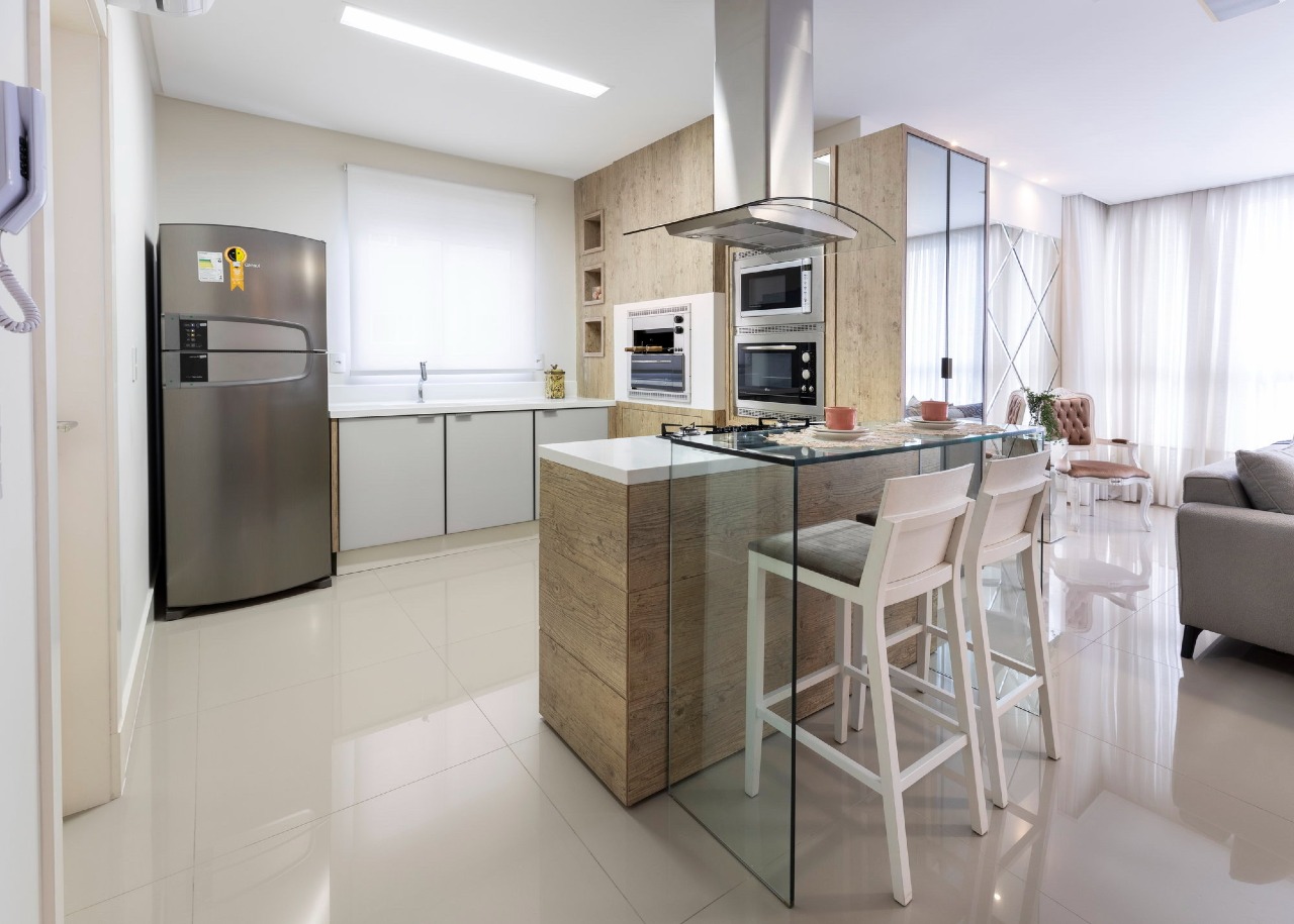 Apartamento à venda no Centro: Cozinha planejada com ilha, coifa, fornos embutidos e bancada de vidro com banquetas